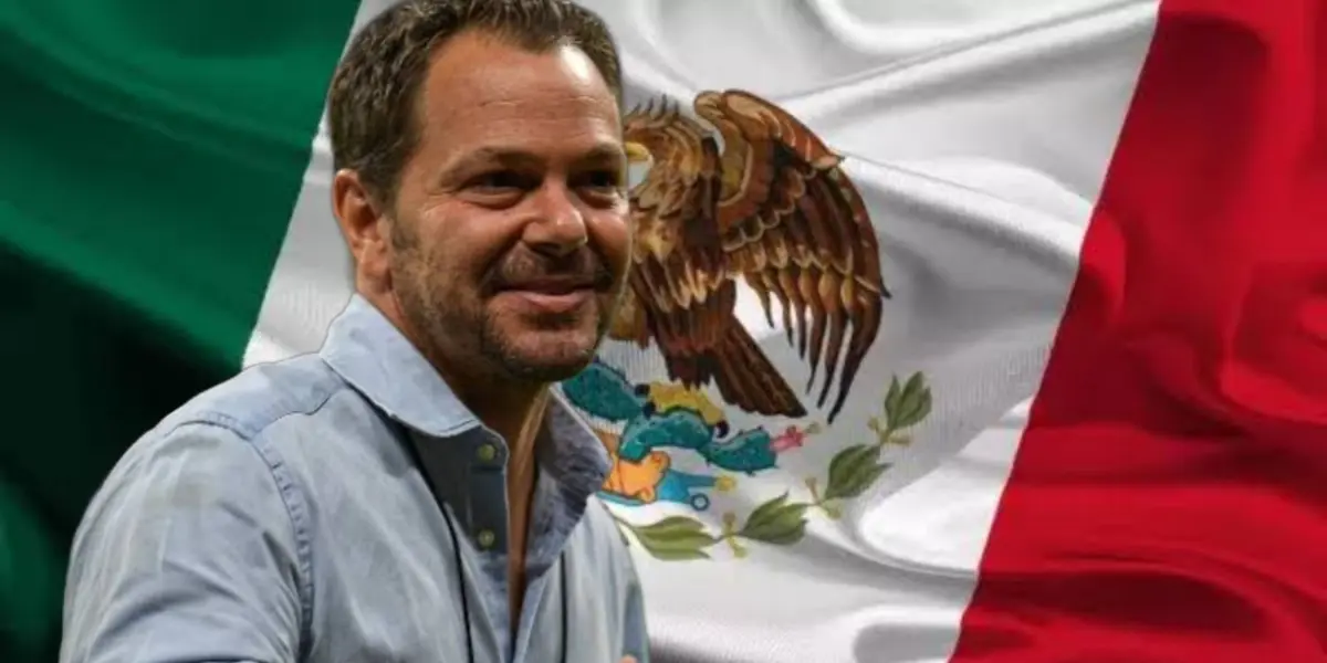 Santiago Baños sonriendo y al fondo la bandera de México / Foto Getty